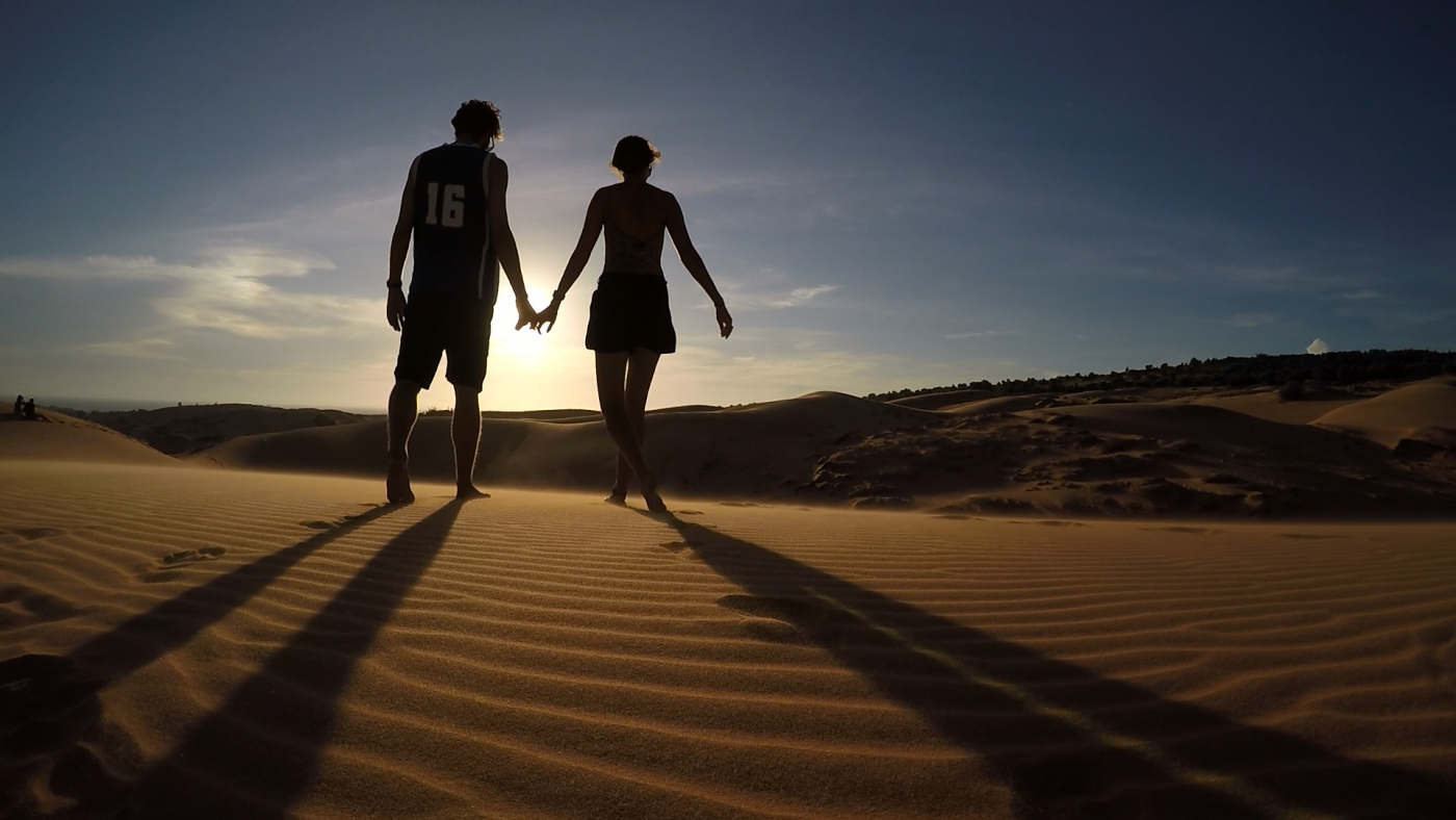 Saving Money for Travel: Couple holding hands in the desert