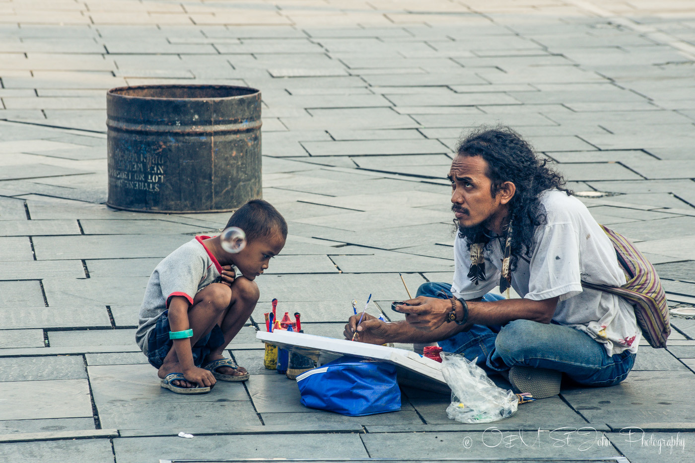 A boy watching a man paint in Taman Fatahilah, Old Jakarta