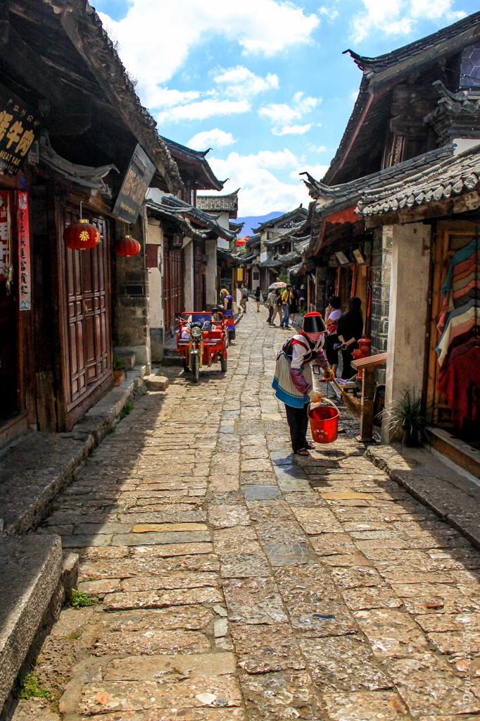 Woman cleaning in front of her shop in Lijiang, China