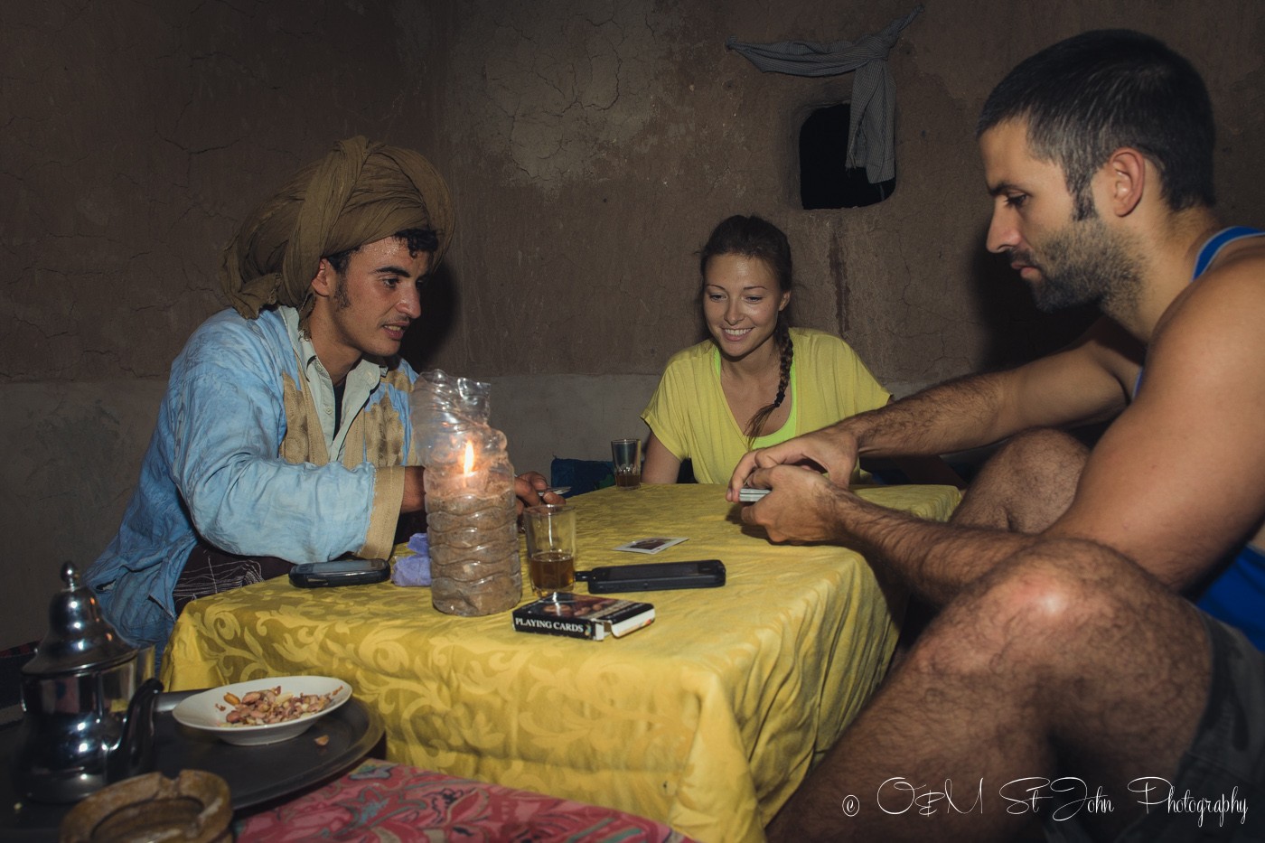 Max and Oksana playing cards with Muhamed in nomad hut in Erg Chebbi. Sahara Desert. Morocco