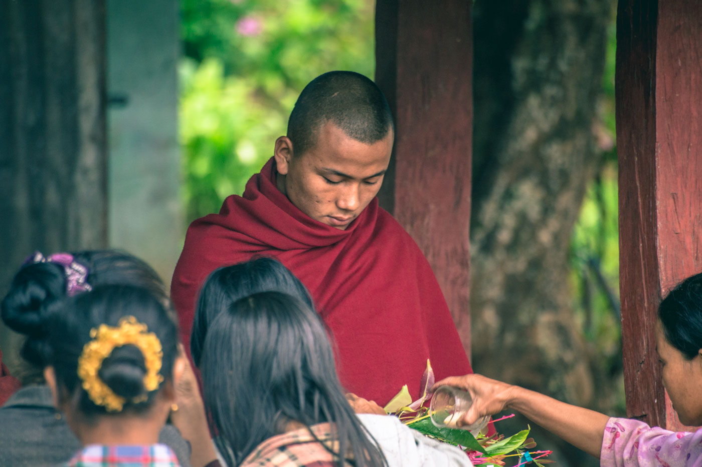 Burmese monk collecting offerings from the local people outside of the monastery in Myanmar.