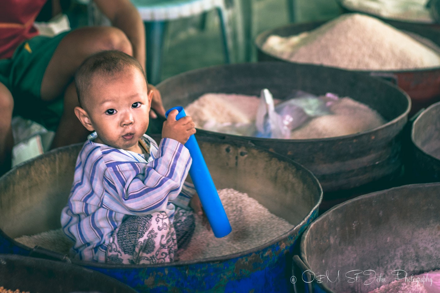 Baby in a rice bucket at the market in Myanmar