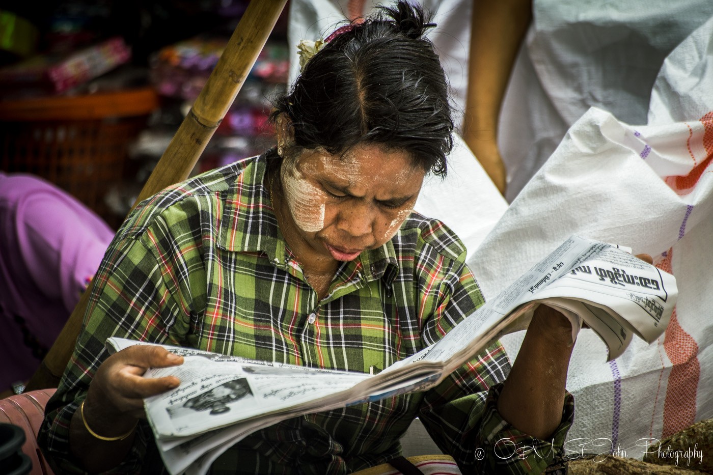 3 days in Yangon: Woman with thanaka paste on her cheeks is reading a local newspaper. Yangon, Myanmar