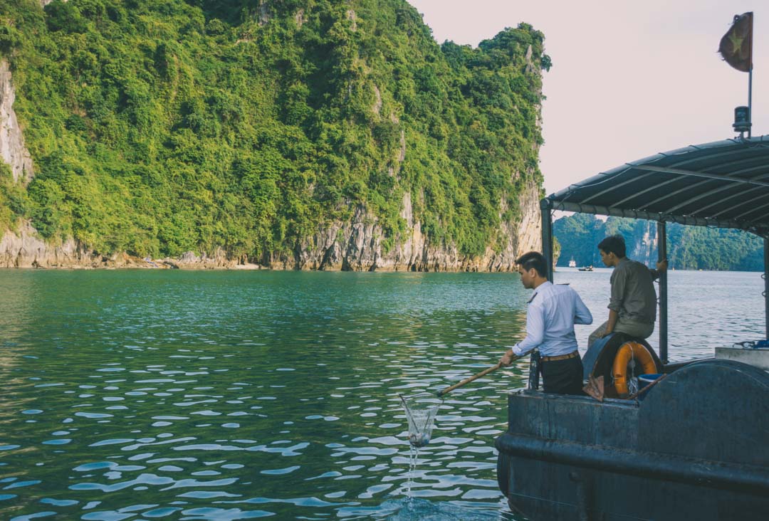 Halong Bay cruise. Indochina Junk - Dragon Legend staff collecting garbage at sea